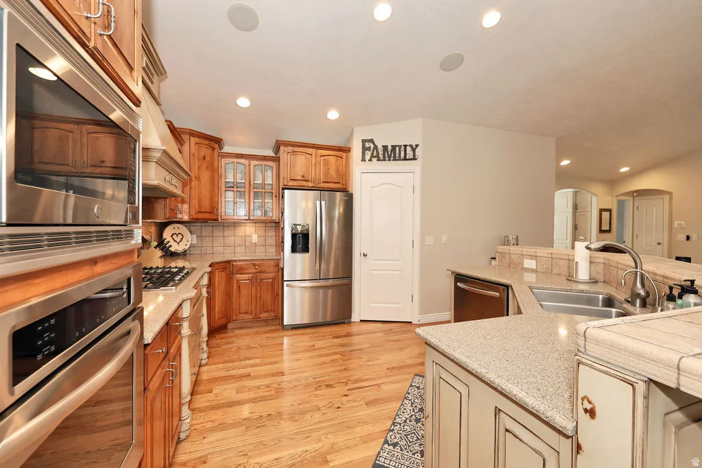 Kitchen featuring wood-finish flooring, stainless steel appliances, light-toned cabinetry, solid surface countertops, and recessed lighting