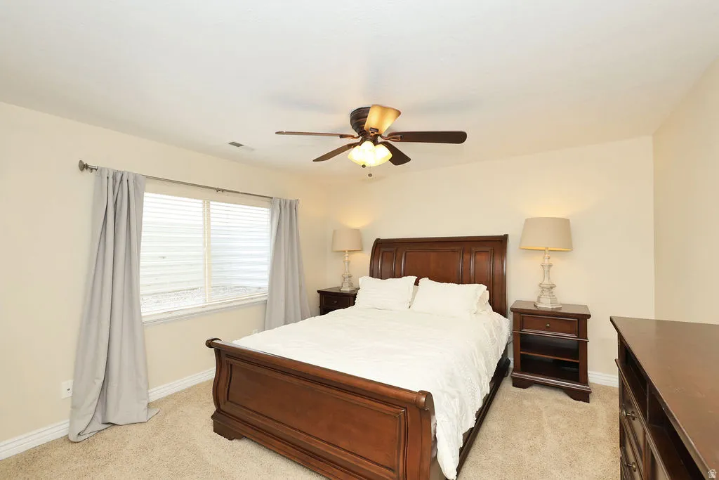 Carpeted room featuring a ceiling fan with integrated lighting, a window with horizontal blinds, and baseboard molding