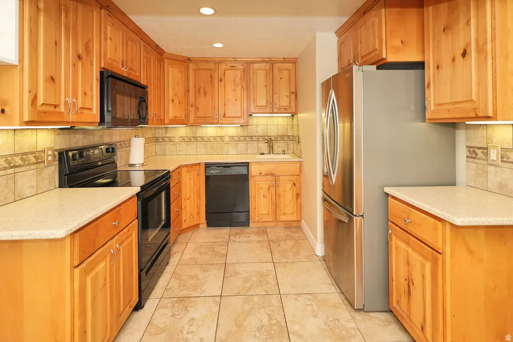 Kitchen featuring wood-finish cabinetry, light-toned countertops, and a tiled backsplash