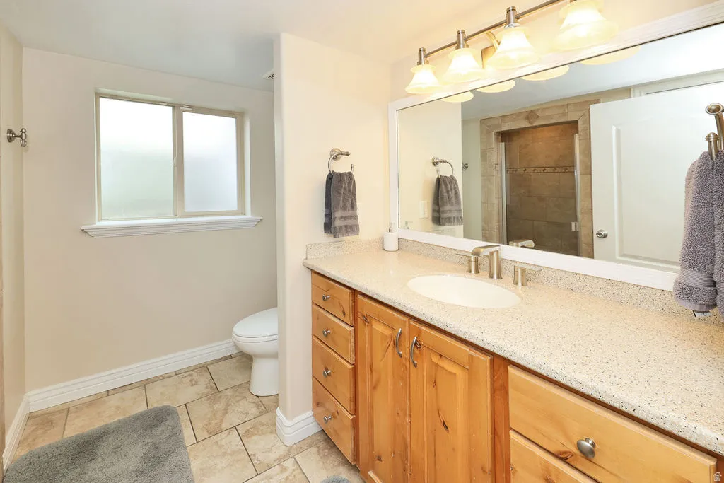 Bathroom featuring a single vanity with wood cabinetry, speckled countertop, and integrated sink