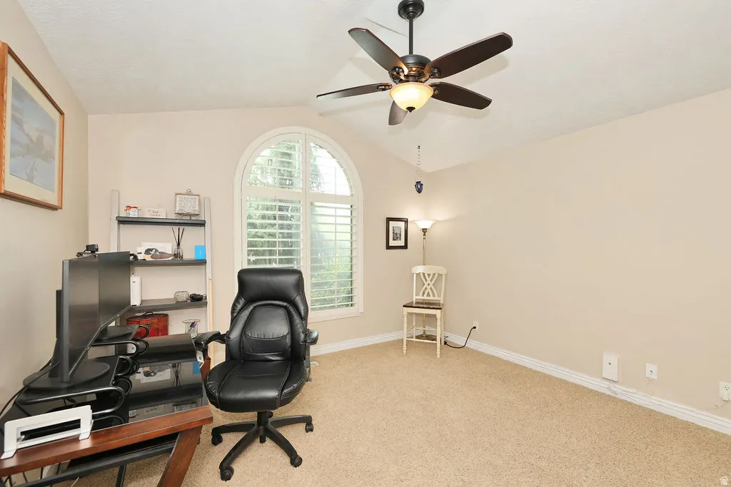 Arched window with plantation shutters, vaulted ceiling, and ceiling fan with integrated lighting