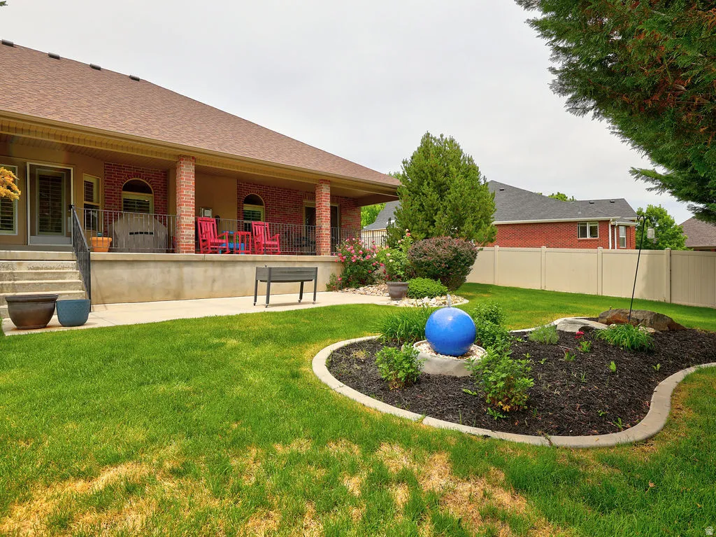 Expansive rear patio featuring brick columns, a concrete floor, and a metal railing