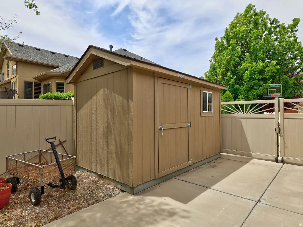 Freestanding shed featuring a composite shingle roof, wood-finish siding, a single window, and double doors with metal hardware