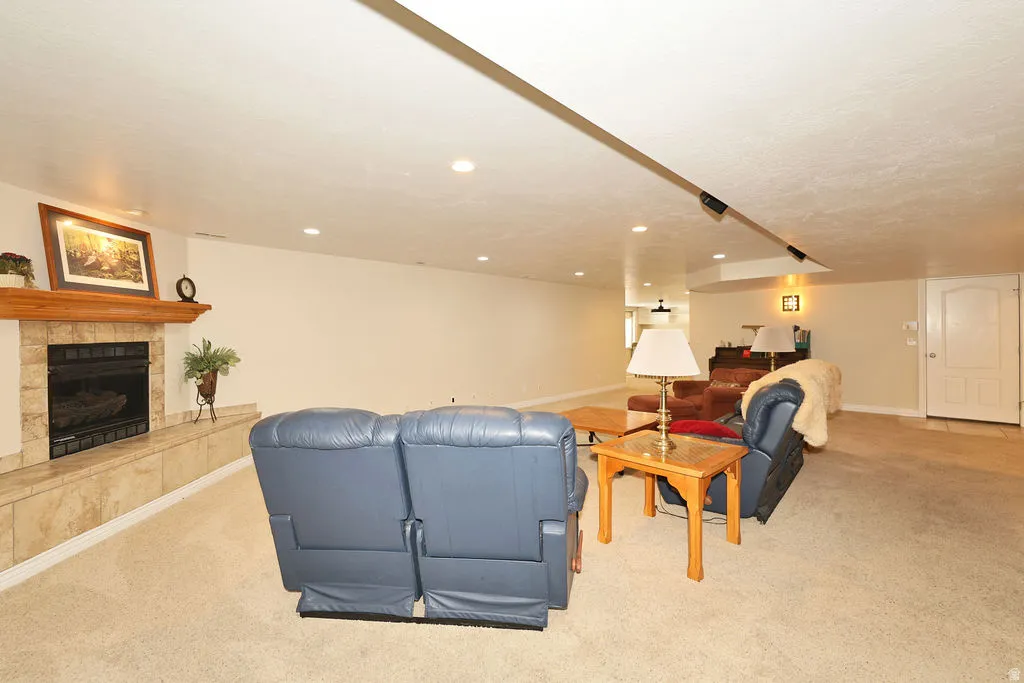 Spacious living area featuring a fireplace with a light-toned tile surround, a wood mantel, and integrated hearth seating