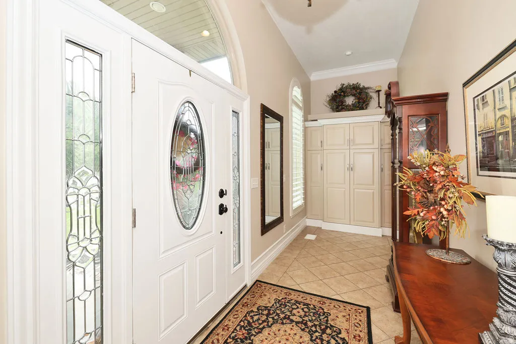 Entryway featuring a white door with decorative glass inserts, flanking sidelights, and an arched transom window