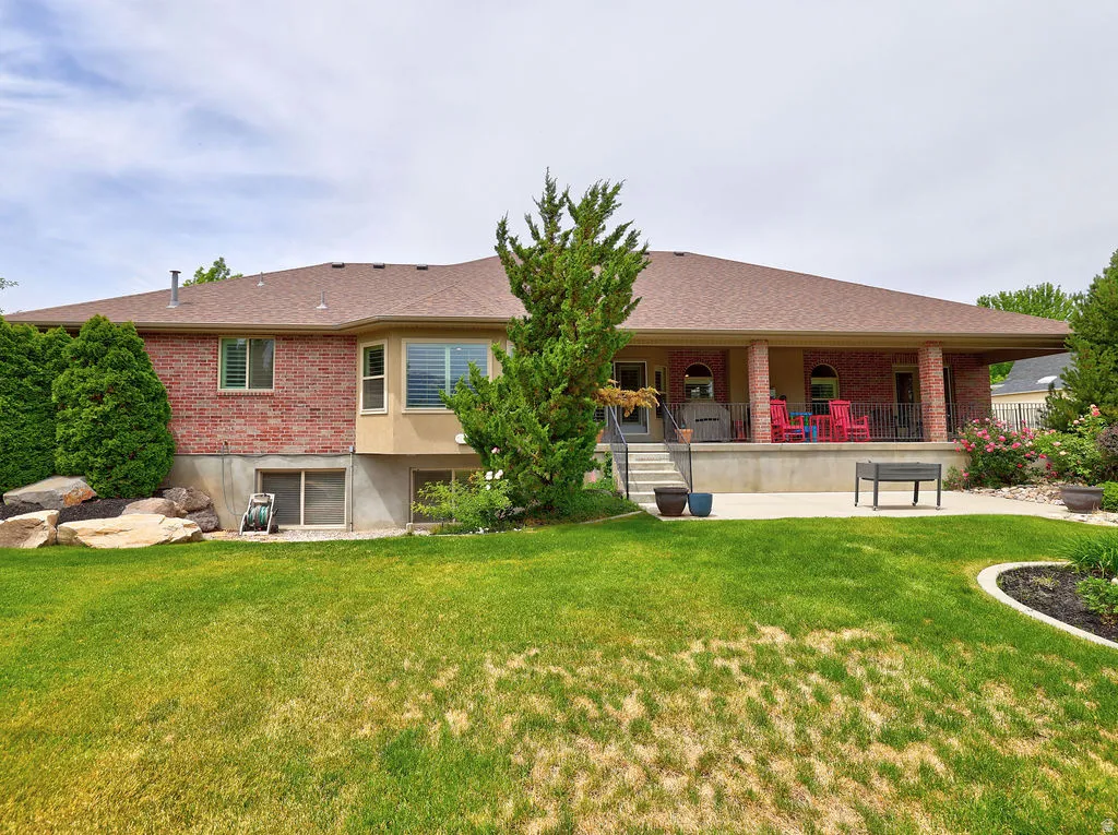 Rear exterior featuring a covered patio with brick columns and a concrete slab