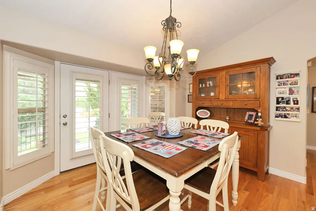 Dining area featuring wood-finish flooring, a vaulted ceiling, and an ornate chandelier