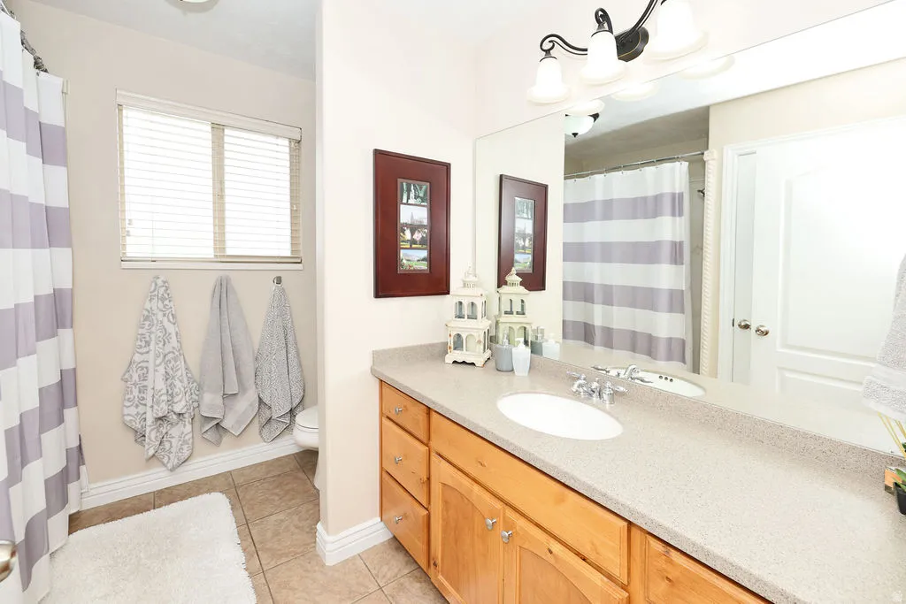 Bathroom featuring a light wood vanity with a light-colored countertop, integrated sink, and an expansive mirror