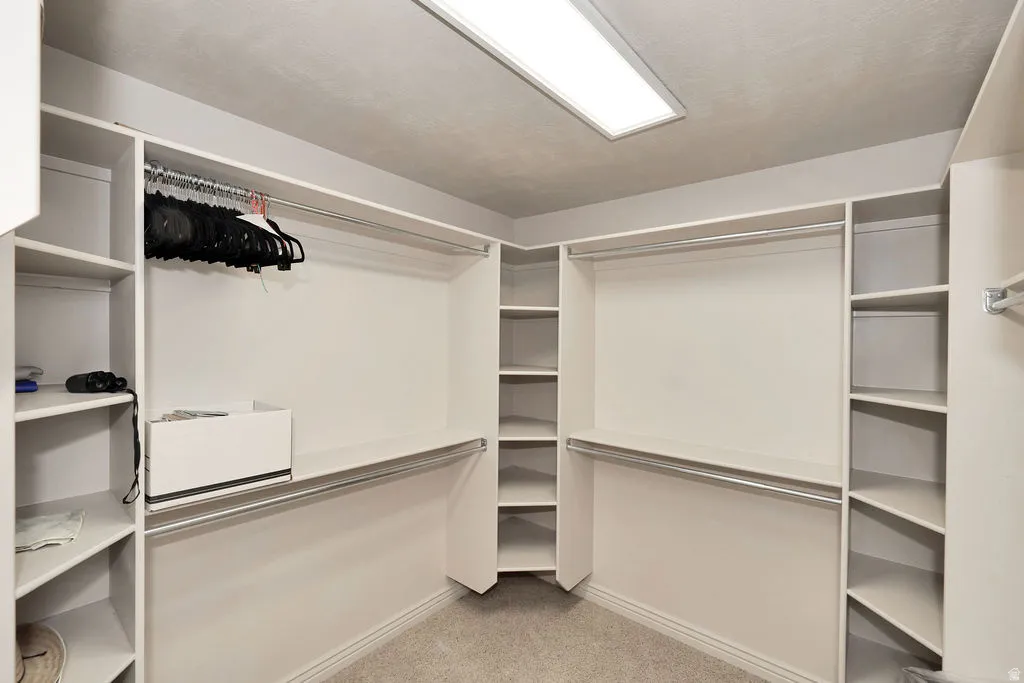 Custom closet system featuring multiple hanging rods, integrated shelving units, dedicated shoe storage, and a flush-mounted ceiling light fixture