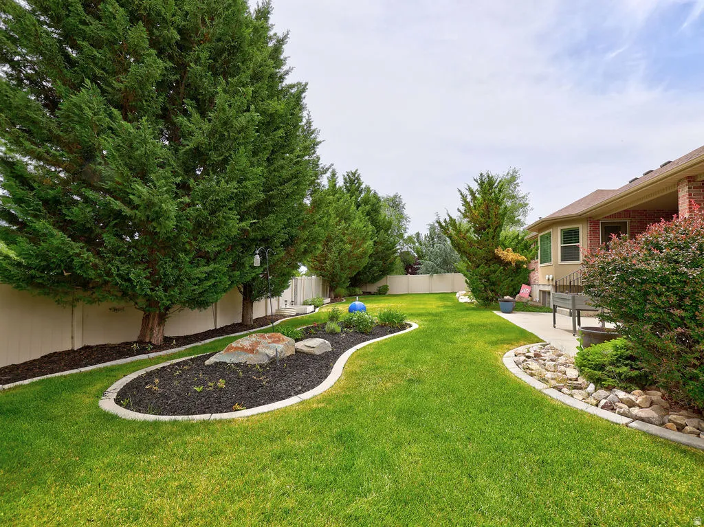 Expansive backyard featuring a lush lawn, mature evergreen trees, and a decorative rock garden