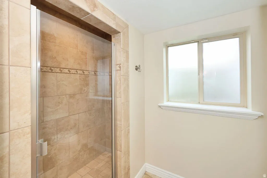 Tiled shower enclosure with a glass door and an accent tile band