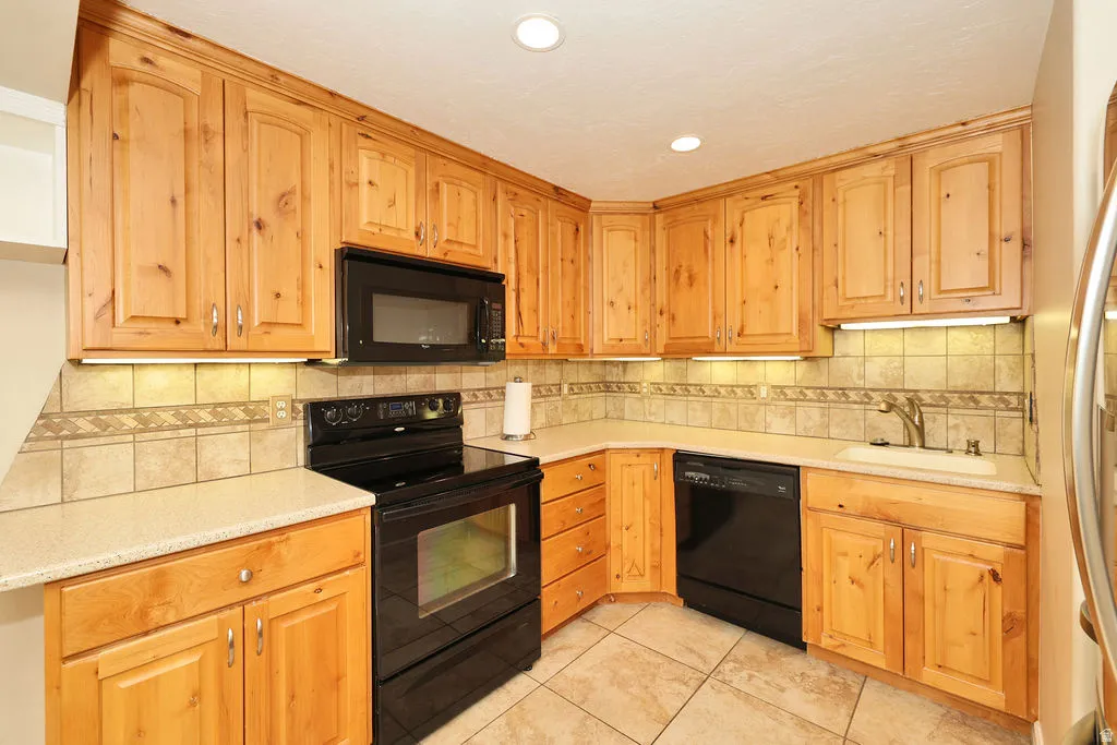 Kitchen featuring wood cabinetry, stone-look countertops, and a tiled backsplash