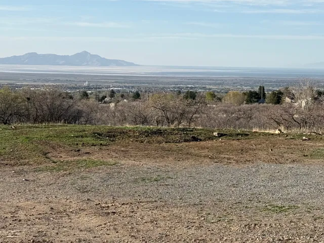 Expansive land parcel with distant mountain ranges and a body of water forming the horizon