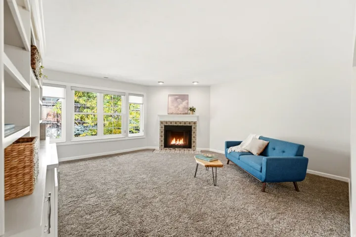 Wall-to-wall carpeting and built-in shelving complement the corner fireplace with a tiled surround