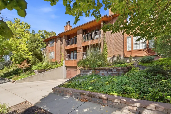 Brick facade with multiple private balconies, wood-finish eaves, and a built-in garage