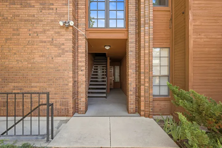 Brick and wood-sided exterior featuring multiple windows and a concrete pathway leading to an entryway