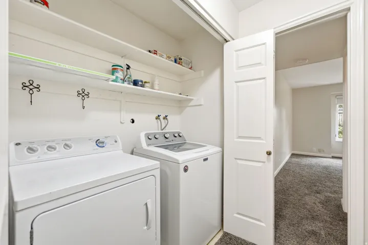 Laundry area with built-in shelving and white appliances