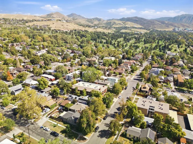 Residential area with varied architectural styles, mature trees, and mountainous backdrop