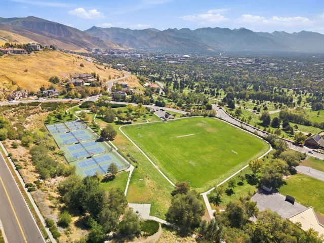 Expansive neighborhood park featuring multiple tennis courts, a large sports field, and paved walking paths