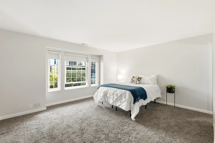 Recessed windows with blinds, light gray wall paint, and gray carpet flooring