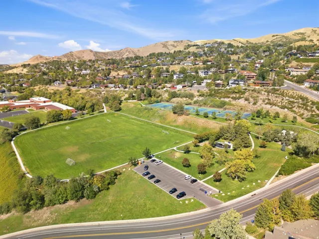 Expansive natural scenery with a manicured sports field, paved parking area, and multi-lane roadway