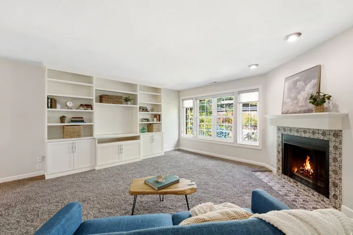 Built-in shelving with integrated cabinetry, recessed lighting, fireplace with tile surround, and multiple windows providing natural light