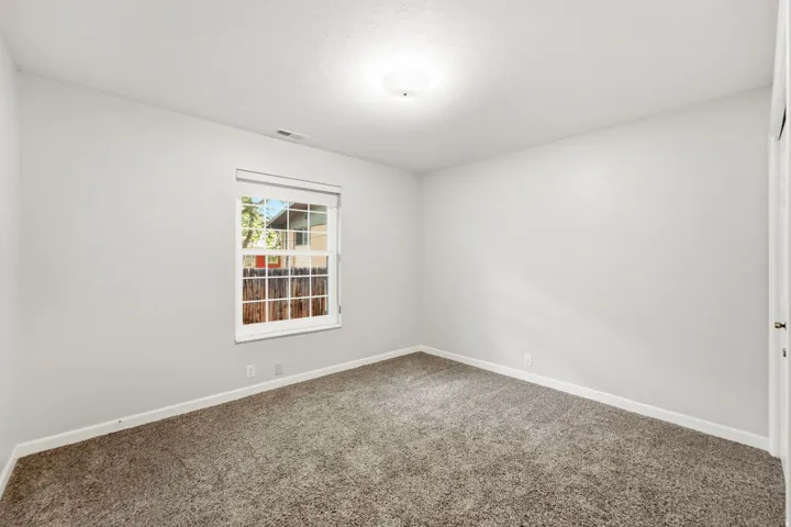 Carpeted flooring, white walls, and a window with white trim and muntins