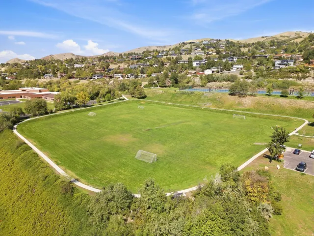 Expansive green space with walking paths, surrounding residential structures, and distant hills