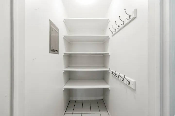 Entryway closet featuring white shelving, white coat hooks, and tiled flooring