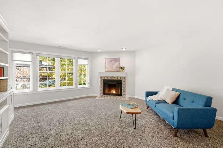 Integrated built-in shelving, a tiled fireplace with mantel, and a bank of large windows