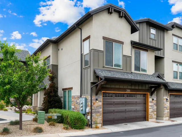 Contemporary townhome exterior featuring multi-toned siding, stone accents, and a dark brown garage door