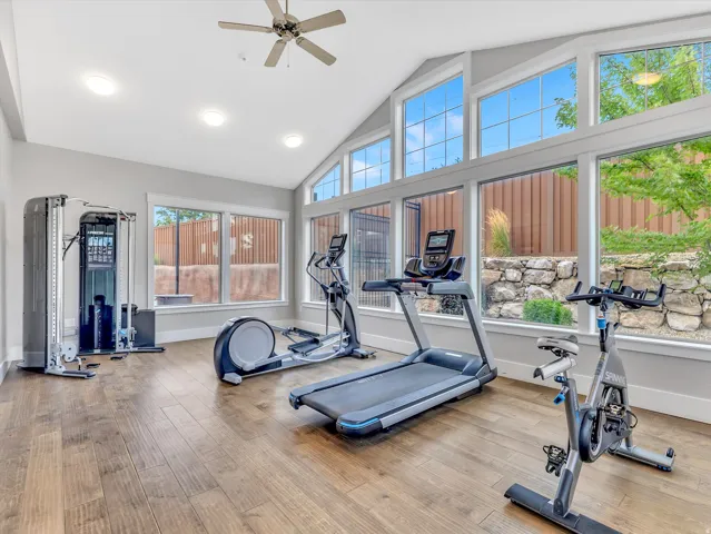Dedicated exercise room featuring wood-finish flooring, vaulted ceilings, and extensive fenestration