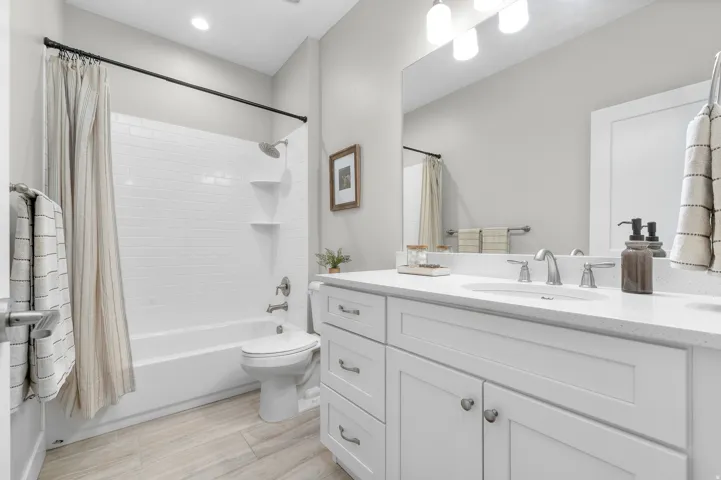 Modern bathroom featuring a white subway tile tub surround, built-in shelving, and a vanity with white cabinetry