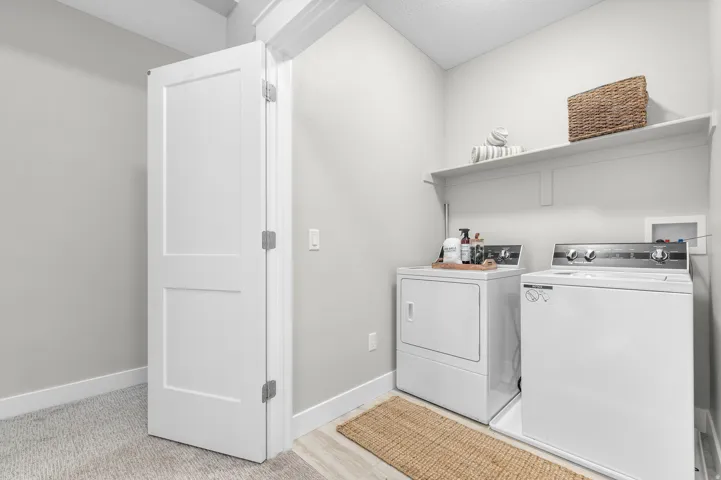 Dedicated laundry area featuring a white two-panel door, light gray walls, built-in shelving, and wood-finish flooring