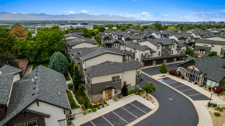 Townhome community featuring multi-level residences with contrasting siding, dark shingle roofing, and mountain backdrop