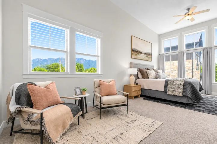 Carpeted bedroom featuring tall ceilings, a ceiling fan, and multiple large windows