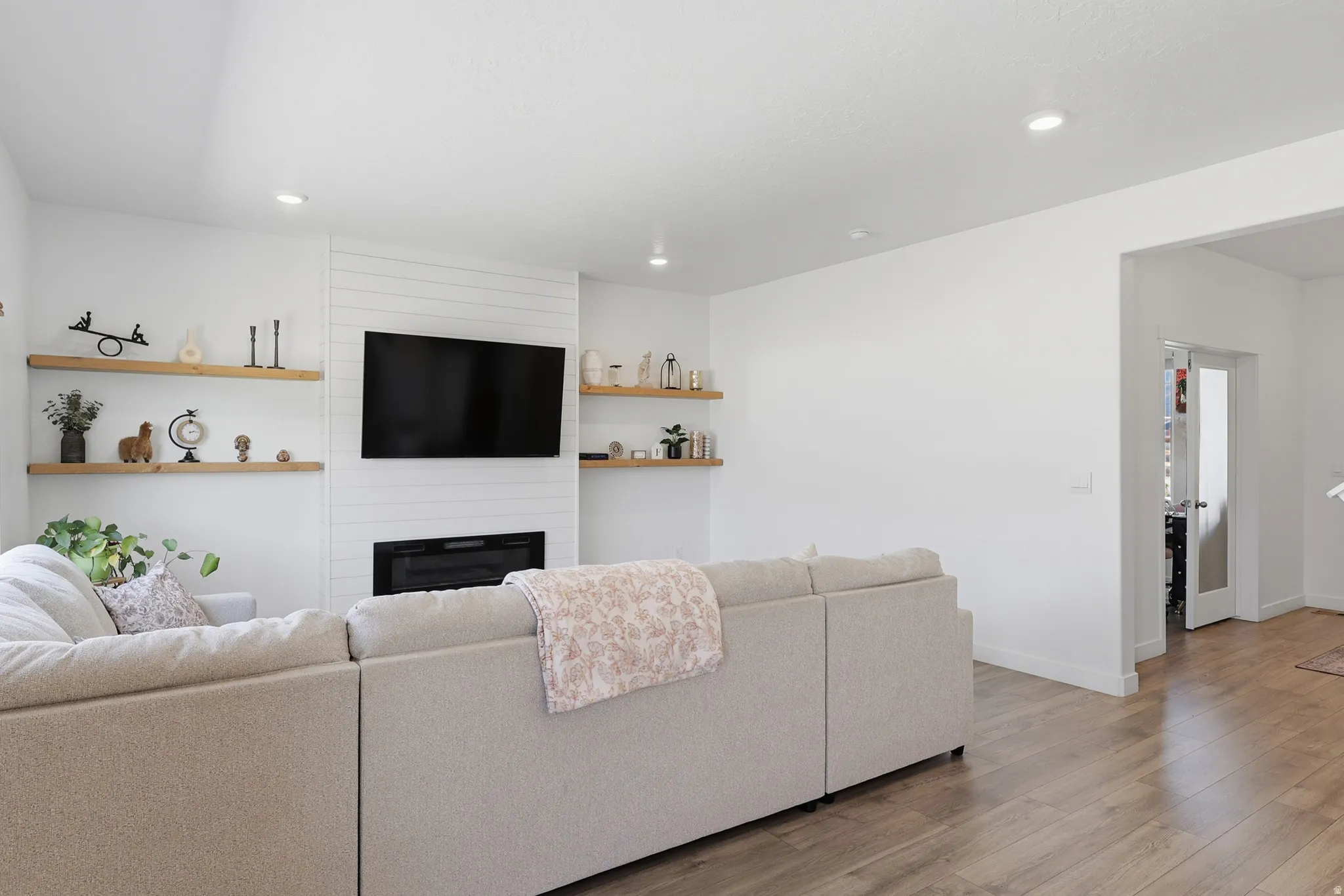 Living area featuring wood-finish flooring, recessed lighting, and a white shiplap fireplace surround
