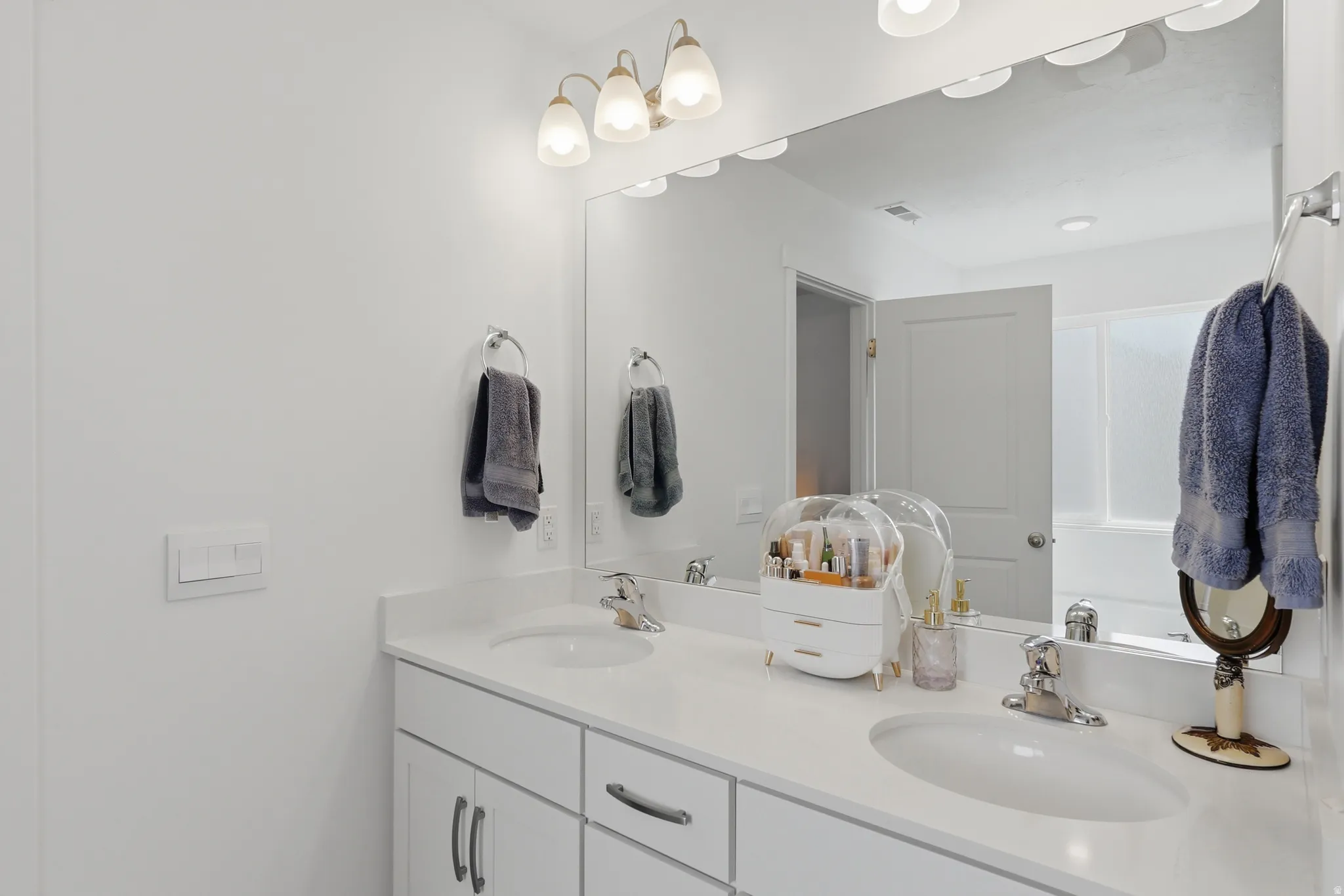 Bathroom featuring a dual vanity with white cabinetry, light-toned countertops, and two undermount sinks
