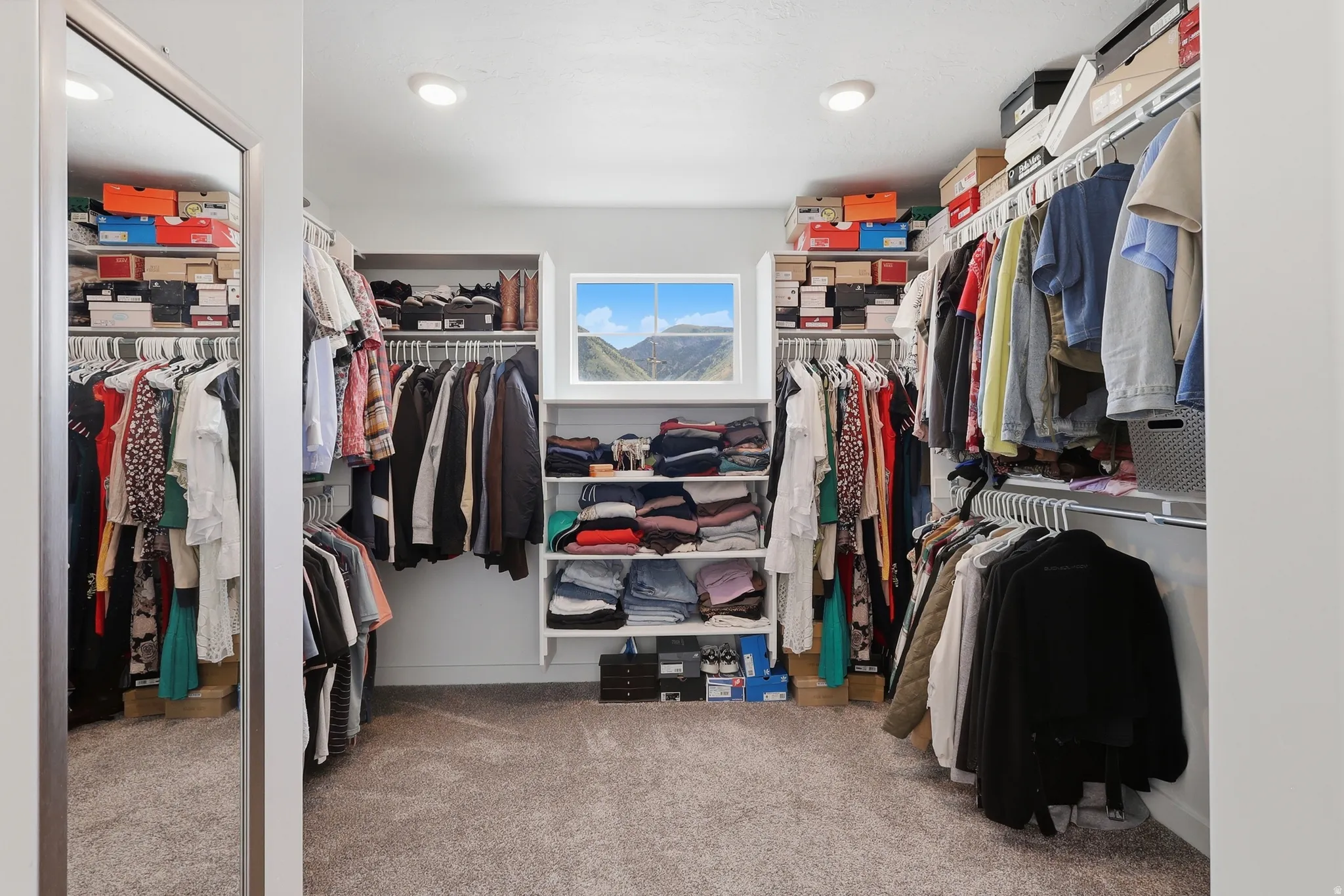 Walk-in closet featuring carpet flooring, recessed lighting, and a white-framed window