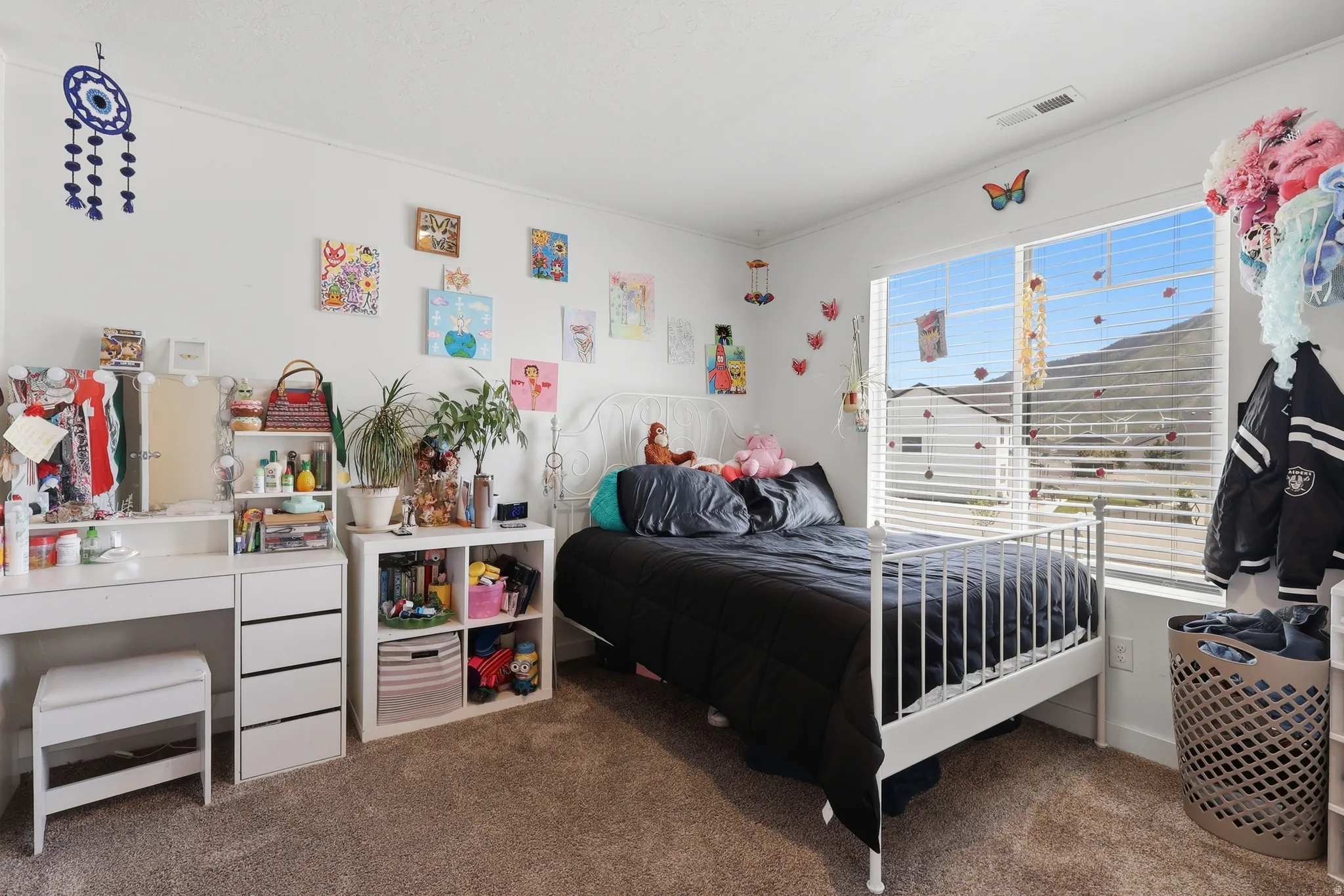 Carpeted room featuring a large window with horizontal blinds, built-in shelving, and a mountain backdrop