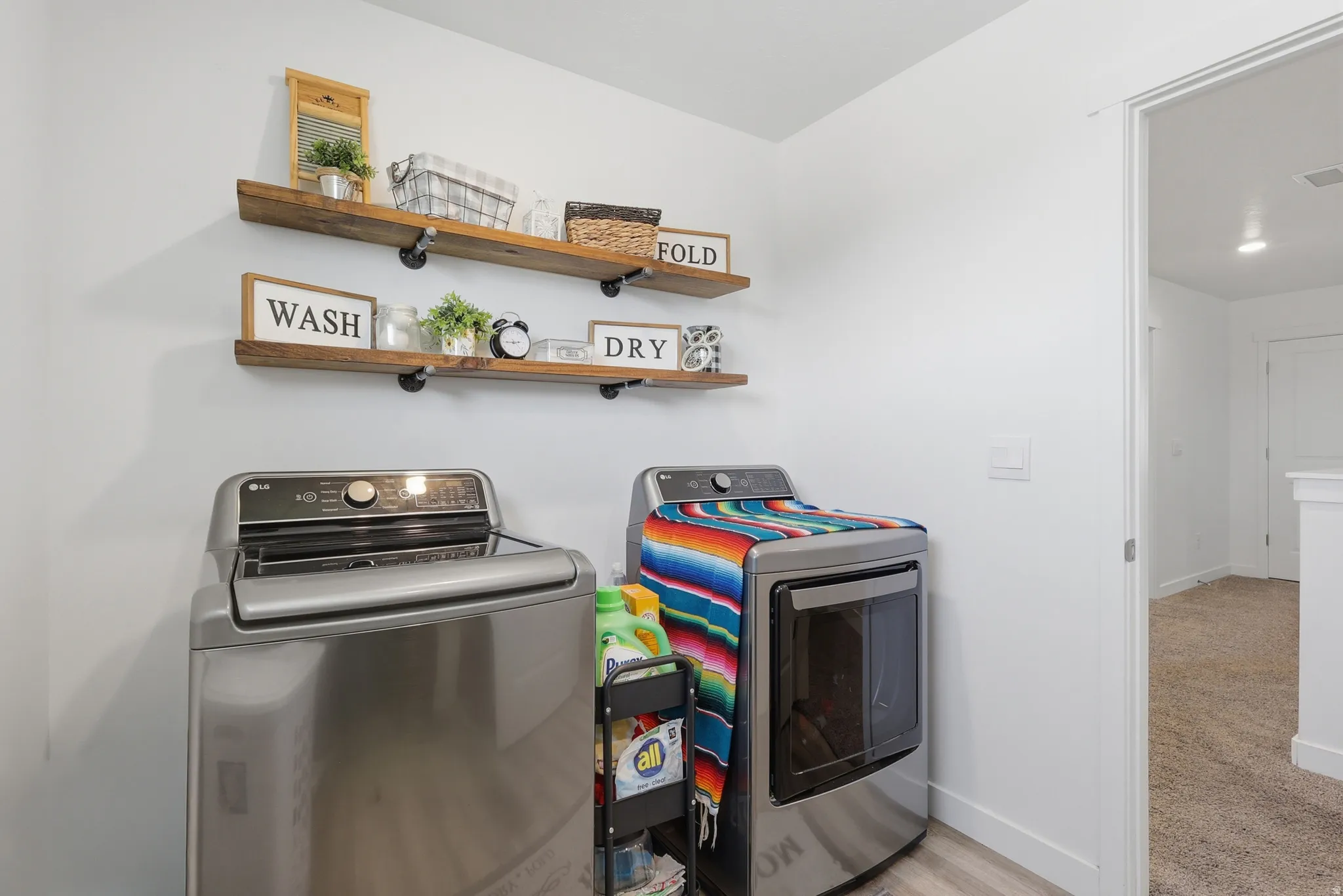 Dedicated laundry area featuring a light wood-finish floor and white walls