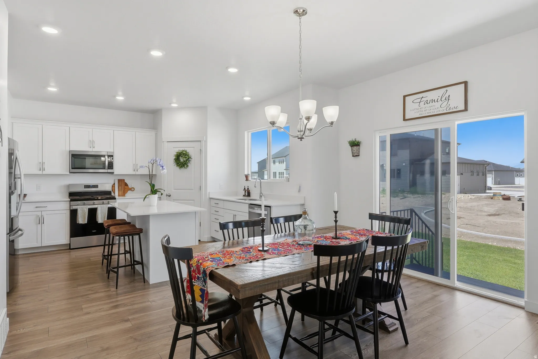 Open-concept living space featuring wood-finish flooring, a contemporary dining chandelier, and recessed lighting