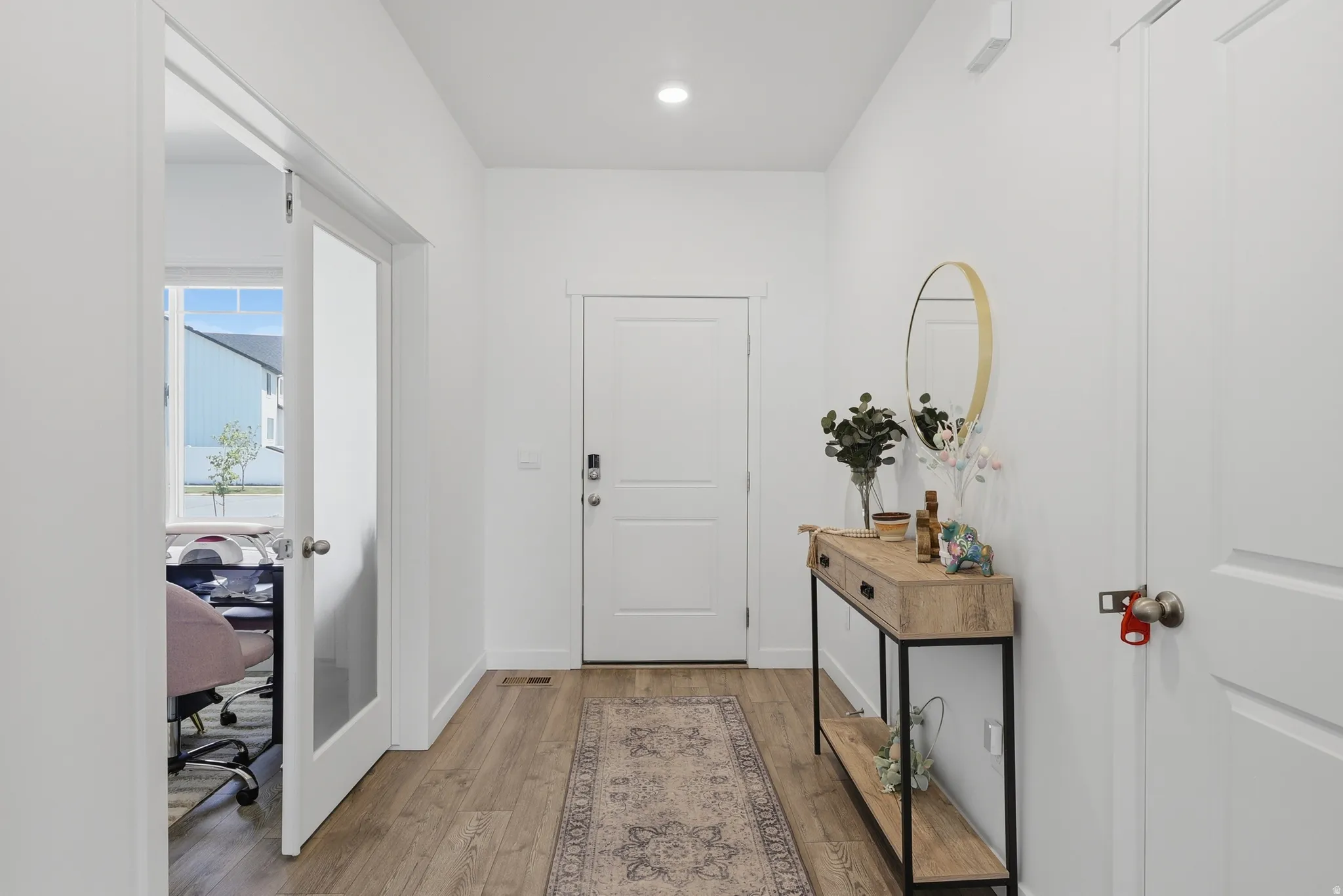 Entryway featuring wood-finish flooring, white paneled doors, and a glass-paneled interior door