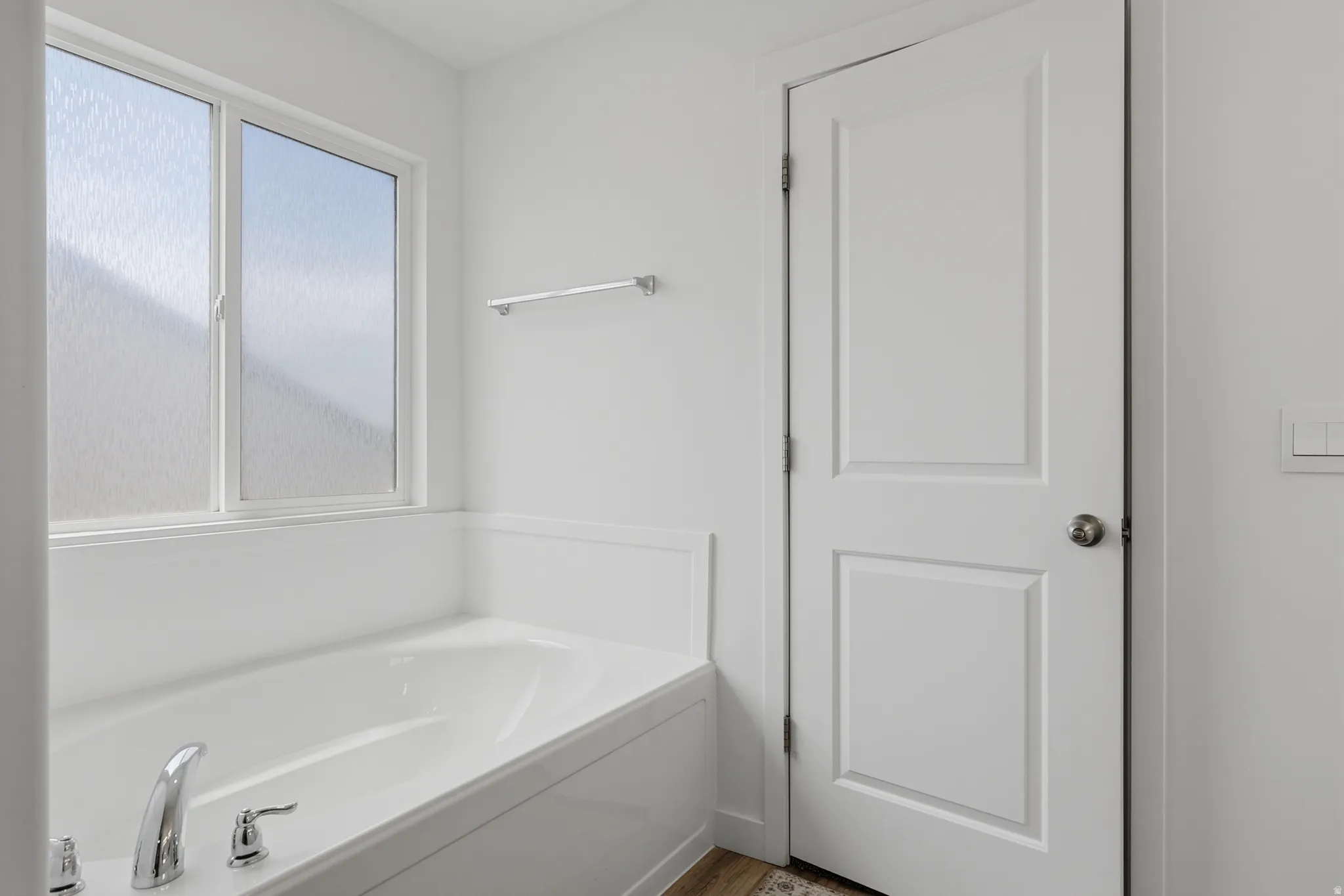 Integrated bathtub featuring a polished chrome faucet and a large window with textured privacy glass
