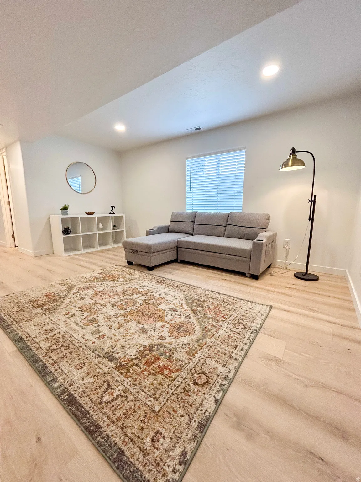 Bright living area featuring wood-finish flooring, recessed lighting, and a window with blinds