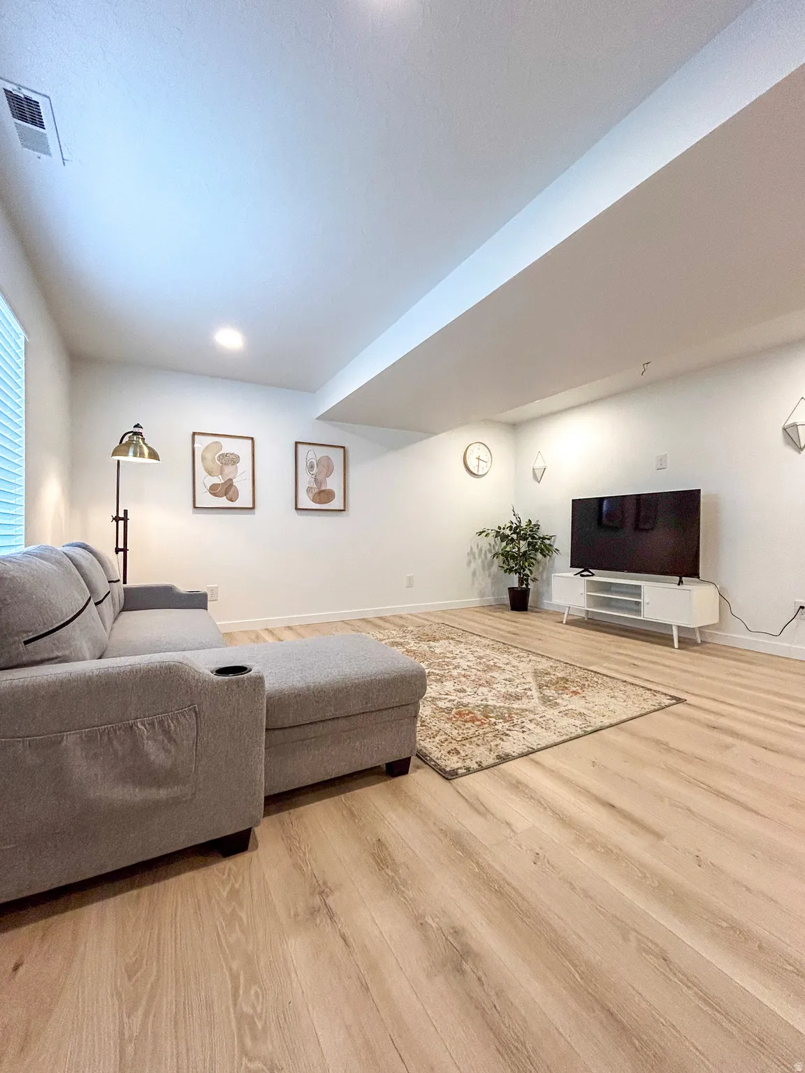 Spacious room featuring light wood-finish flooring, white walls, and recessed lighting