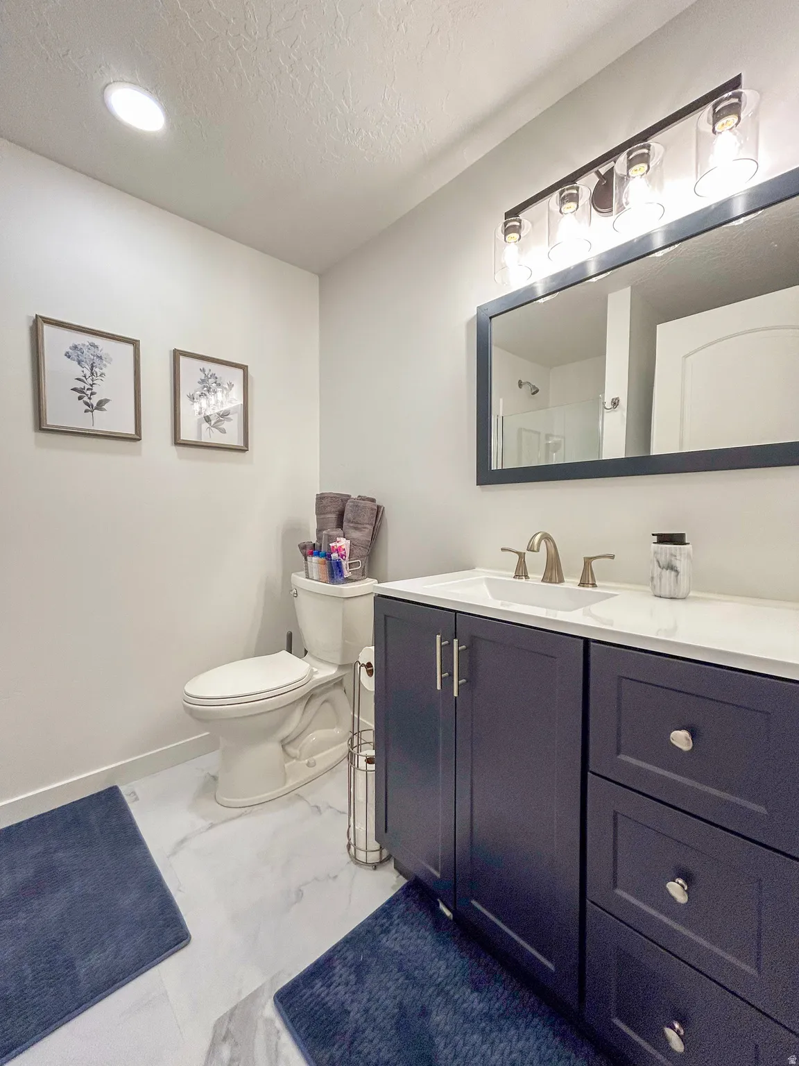 Bathroom featuring a dark blue vanity with silver hardware, a white countertop, and a rectangular undermount sink