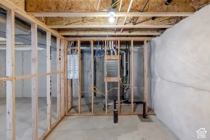 Unfinished interior space featuring exposed wood-stud framing, concrete flooring, concrete block walls with insulation wrap, and accessible mechanical infrastructure