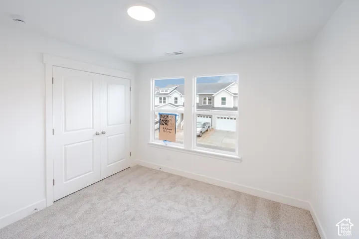 Neutral interior featuring crisp white walls, neutral-toned carpeting, double-panel closet doors, and dual-pane windows