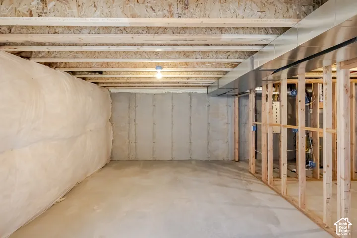 Unfinished space featuring exposed timber framing, concrete flooring, plastic-wrapped insulation, and exposed metal ductwork